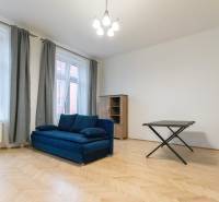 Obývací pokoj s modrou sedačkou a podlahou s dřevěným dekorem ve 3-pokojovém bytě.