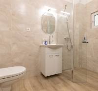 Koupelna s podlahou s dřevěným dekorem, sprchou a skříní v 3-pokojovém bytě.