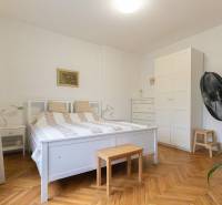 Ložnice v 2-pokojovém bytě s bílým nábytkem a podlahou s dřevěným dekorem.