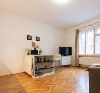 Obývací pokoj v 2pokojovém bytě se světlým nábytkem a podlahou s dřevěným dekorem.