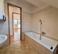 Koupelna s dlažbou vedle 2pokojového bytu, vana a umyvadlo, prostorné uspořádání.