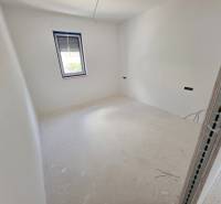 Světlý pokoj s bílými stěnami a oknem značky HR-reality v Rekreačním apartmánu.