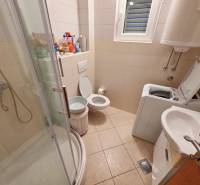 Koupelna v rekreačním apartmánu s toaletou, sprchovým koutem a pračkou.