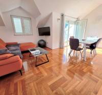 Rekreační apartmán s oranžovou pohovkou, jídelním stolem a podlahou s dřevěným dekorem.