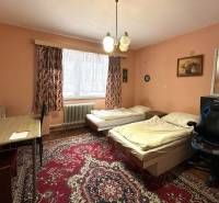 Pokoj v rodinném domě s kobercovou podlahou, dvěma postelemi a stolem.