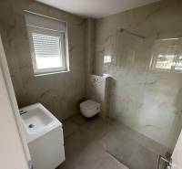Koupelna v 3-pokojovém bytě s umyvadlem, toaletou a sprchovým koutem se skleněnou stěnou.