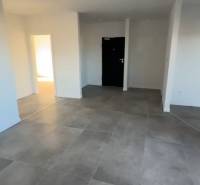 Interiér 3-pokojového bytu s velkými dlaždicemi a bílými stěnami.