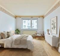 Ložnice s postelí, koberec, křeslo, dekorace, podlaha s dřevěným dekorem.