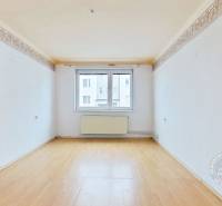 Pokoj s bílými stěnami a podlahou s dřevěným dekorem ve 3-pokojovém bytě.