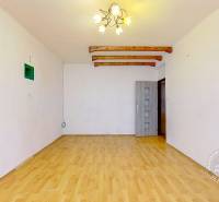 Obývací pokoj v 3-pokojovém bytě s podlahou s dřevěným dekorem a světlým lustrem.