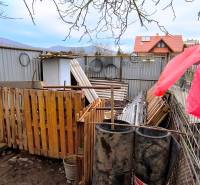 Pozemky - bydlení na Mierové ulici v Krásnohorskom Podhradí s materiály a sudy.