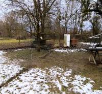 Pozemek na Mírové ulici v Krásnohorské Podhradí s trávou a sněhem, vhodný k bydlení.