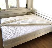 Světlá ložnice s bílou postelí a podlahou s dřevěným dekorem v 2-pokojovém bytě.