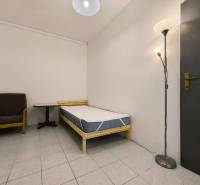 Jednolůžkový pokoj s křeslem a stojací lampou v rodinném domě.