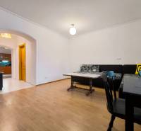 Obývací pokoj v rodinném domě s podlahou s dřevěným dekorem, sedačkou a jídelním stolem.