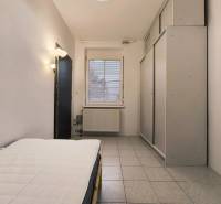 Ložnice v rodinném domě s postelí, vestavěnou skříní a dlažbou.