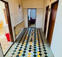 Chodba s barevnou dlažbou v rodinném domě s dřevěnými dveřmi a radiátorem.