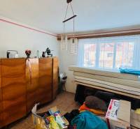 Pokoj v rodinném domě s dřevěným nábytkem, lustr a okno s výhledem.