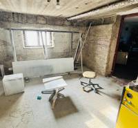 Suterénní prostor v rodinném domě s jednoduchým nábytkem a oknem.