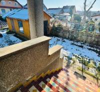 Zahrada rodinného domu ve Velkých Bielicích v Partizánském, s přístřeškem a sněhovou pokrývkou.