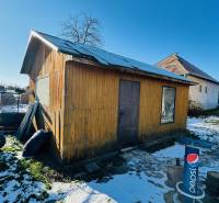 Za domem v Partizánskem, Velkých Bielicích, stojí dřevěná chatka na zasněženém dvoře.