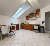 Světlá kuchyně v rodinném domě s dřevěnými skříňkami a střešním oknem.