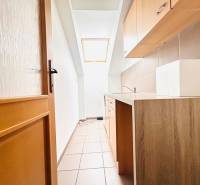 Úzká kuchyňská část v kanceláři s oknem a podlahou s dřevěným dekorem.