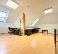 Kanceláře s podlahou s dřevěným dekorem, stoly, židlemi a střešními okny.