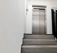 Schodiště k výtahu v budově s 3pokojovým bytem, světlý prostor.