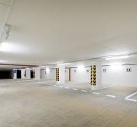 Podzemní parkoviště s jasným osvětlením a vyhrazenými parkovacími místy.