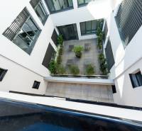 Vnitřní dvůr bytového komplexu v Nitře s terasovou dlažbou a zelení.