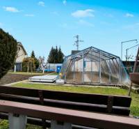 Zahrada v Partizánskom s fóliovníkem, trávou a malým záhonem.