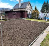 Zahrada s chatou v Partizánskom, připravený záhon, okolní zeleň a dřevěný domek.