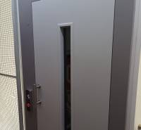 Šedé dveře se skleněným průzorem a tlačítkem výtahu, foto v 1-pokojovém bytě.