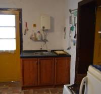 Kuchyně v rodinném domě s dřevěnými skříňkami a podlahou s dřevěným dekorem.