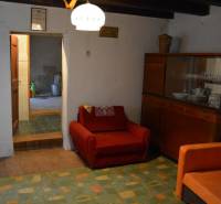 Obývací pokoj v rodinném domě s červeným křeslem a skříňkou s nádobím.