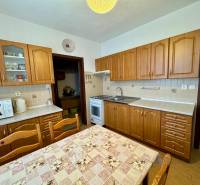 Kuchyně s dřevěnými skříňkami a jídelním stolem, vhodná pro 3pokojový byt.