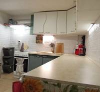 Kuchyně v rodinném domě s bílými cihlovými stěnami a kuchyňskými spotřebiči.