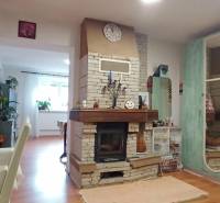 Interiér rodinného domu s krbem a podlahou s dřevěným dekorem, doplněný pestrou výzdobou.