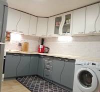 Kuchyně v rodinném domě s bílými a šedými skříňkami, podlaha s dřevěným dekorem.