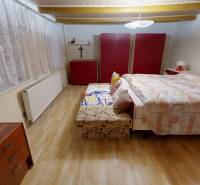 Ložnice v rodinném domě s postelí, šatními skříněmi a podlahou s dřevěným dekorem.