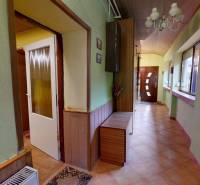 Chodba s dlažbou, dekoracemi a závěsným svítidlem v rodinném domě.