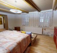 Pokoj v rodinném domě s podlahou s dřevěným dekorem, postelí a červenou skříní.