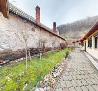 Rodinný dům na Hlavní ulici v Hronském Beňadiku s dlážděným chodníkem vedle trávníku.