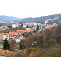 Pohled na vesnici Hronský Beňadik s rodinnými domy na Hlavní ulici obklopenou přírodní scenérií.
