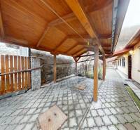 Dvoustranná terasa rodinného domu na Hlavní ulici v Hronském Beňadiku s dřevěným přístřeškem.