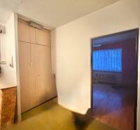 Chodba s vestavěnou skříní v 3-pokojovém bytě, vstup do pokoje s podlahou s dřevěným dekorem.