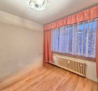 Pokoj v 3pokojovém bytě s podlahou s dřevěným dekorem a závěsy.