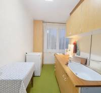 Kuchyně ve 3-pokojovém bytě s jednoduchým zařízením, podlaha s dřevěným dekorem.