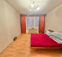 Ložnice v 3-pokojovém bytě s postelí, podlahou s dřevěným dekorem a světlem.